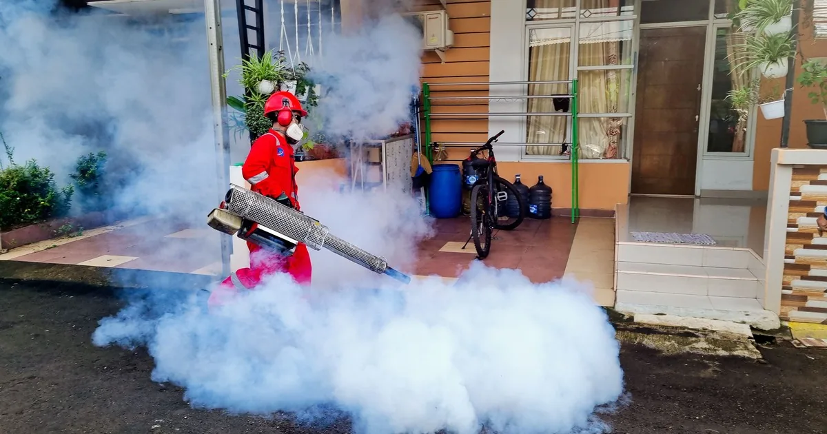 Pest control technician working outside a house with treatment equipment