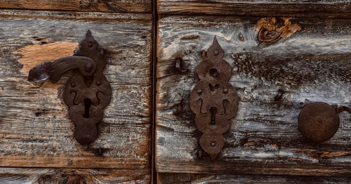 Vintage metal lock plate and keyhole on a weathered wooden door