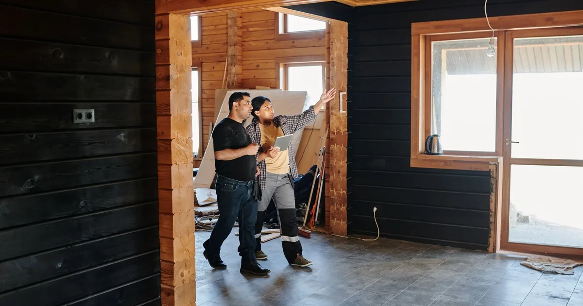 Two people reviewing an interior renovation inside a wood-framed room