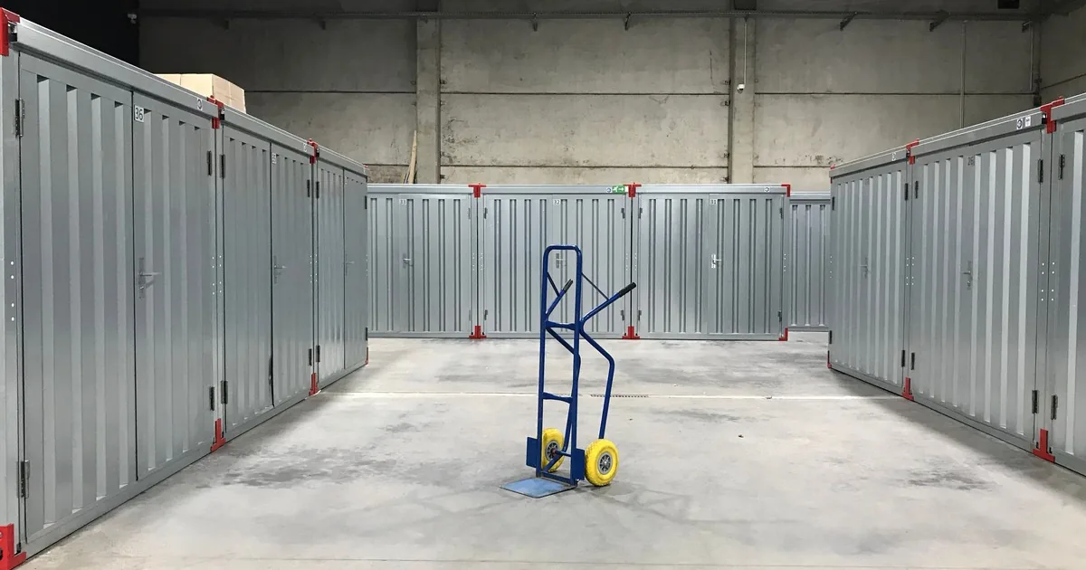 Blue hand truck between rows of steel doors at a self-storage facility