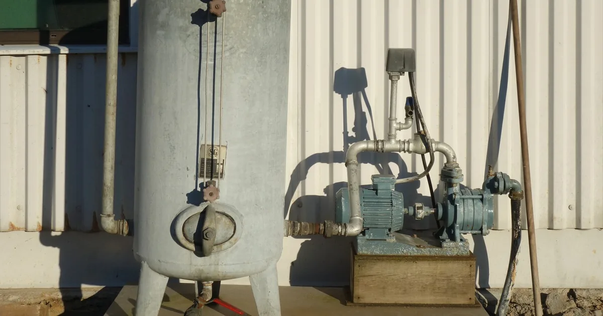 Water well pump and pressure tank outdoors in warm evening light
